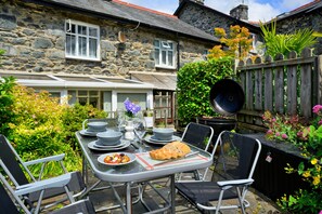 A stone house with a garden patio, outdoor dining set, and a wooden fence. - Artro View (Llanbedr)