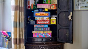 A wooden cabinet with various board games and educational materials. - Artro View (Llanbedr)
