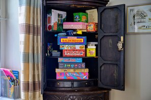 A wooden cabinet with various board games and educational materials. - Artro View (Llanbedr)