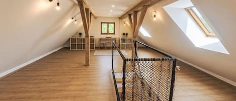 A spacious attic room with wooden beams, a skylight, and a hammock.