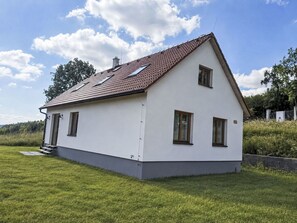 A single-story house with a sloped roof, a small porch, and a grassy yard.