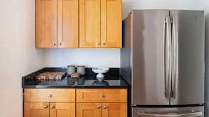 Una cucina con mobili in legno, un frigorifero in acciaio inossidabile e un piano di lavoro nero.