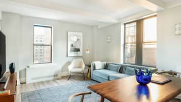 Un salon moderne avec une table à manger en bois, un canapé bleu et un fauteuil blanc.