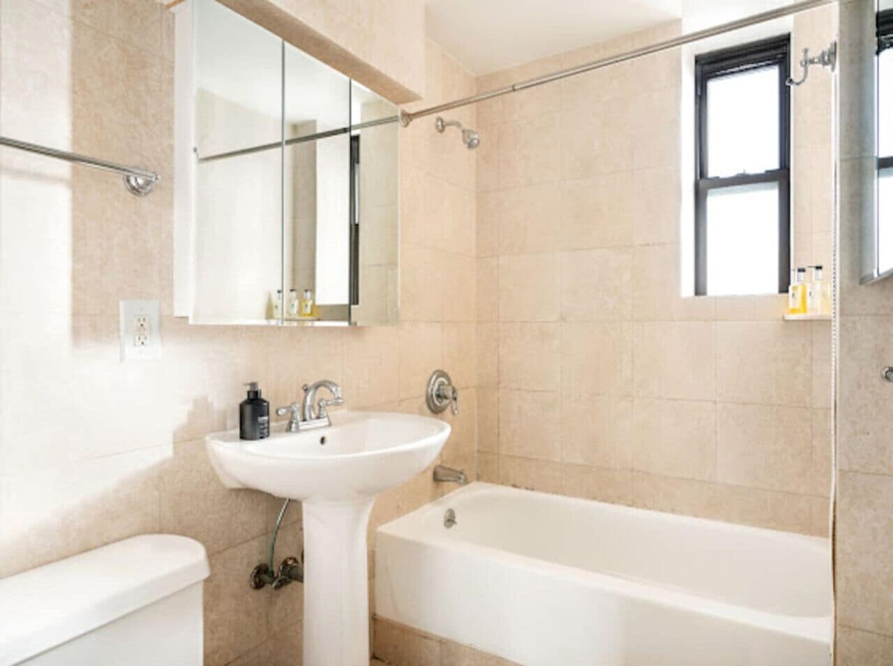 Une salle de bain avec une baignoire, un lavabo, un miroir et une fenêtre.