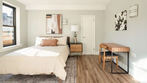 Una camera da letto con un letto, un comodino, un tavolo e una porta.