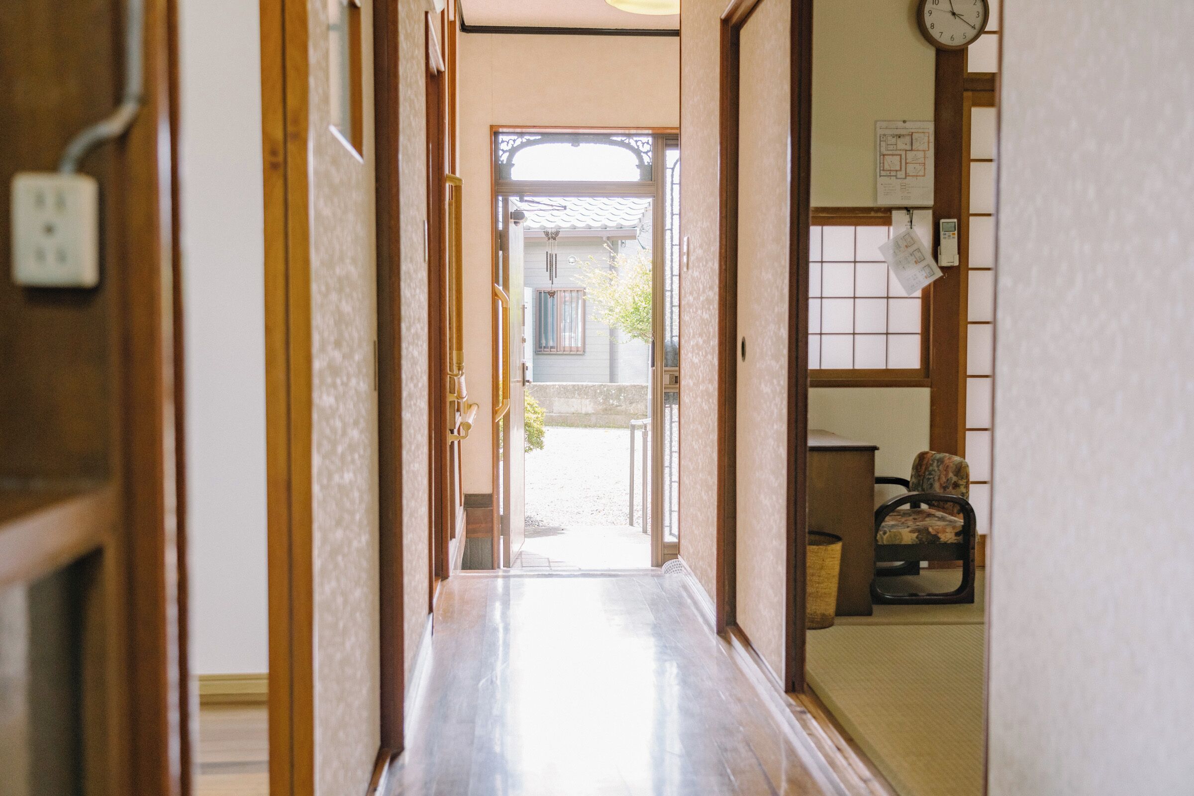 Et traditionelt japansk interiør med skydedøre, trægulv og udsigt gennem et vindue.