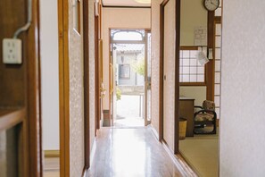 Ein traditionelles japanisches Interieur mit Schiebetüren, Holzboden und Blick durch ein Fenster.