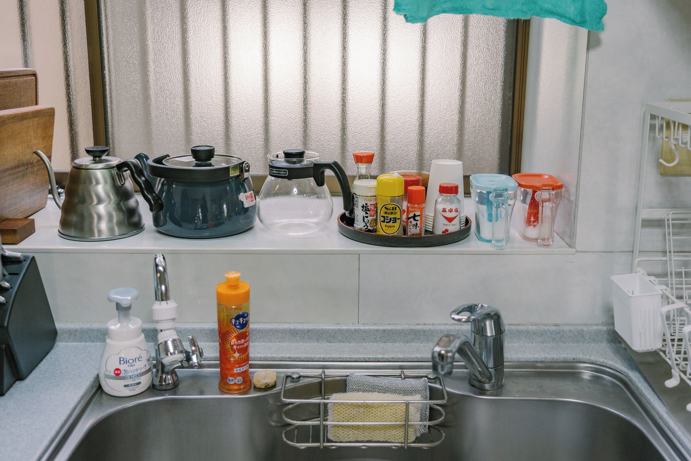 A kitchen with a sink, various utensils, and containers on the countertop.