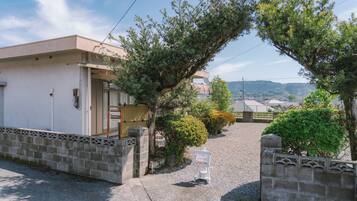 A residential building with a gravel driveway, a gated entrance, and a sign indicating parking.
