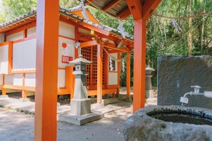 A traditional Japanese shrine with a stone lantern, wooden torii gate, and a stone well.