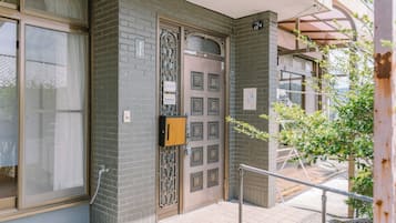 Une entrée d’immeuble avec un portail en métal, une porte en bois et une petite boîte aux lettres.