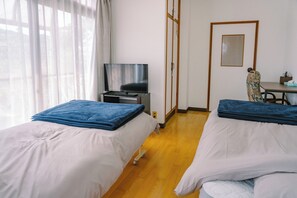 A hotel room with two beds, a television, a desk, and a chair.