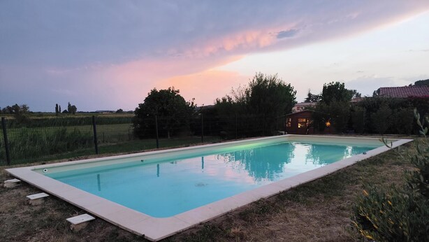 A rectangular swimming pool with a tiled edge, surrounded by a grassy area and a fence. - Just 30 minutes from the river, a countryside vacation rental with a view of Mont Ventoux! (Piolenc)