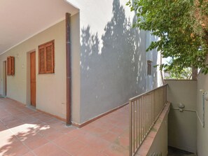 Um corredor com piso de azulejos, persianas de madeira e guarda-corpo de metal.