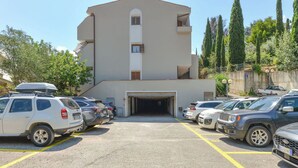 Um estacionamento com vários carros e um edifício com entrada para garagem.