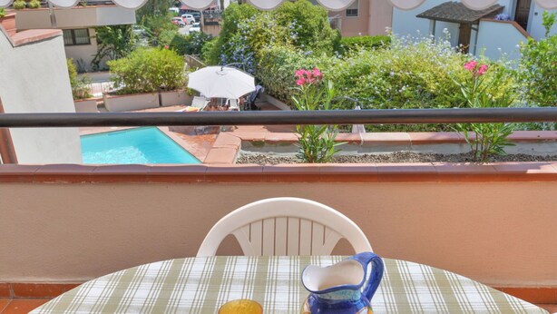 Uma varanda com uma mesa posta para dois, uma piscina e vista da região.