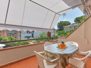 Eine Terrasse mit einem Tisch für zwei Personen, einem weißen Stuhl und einem kleinen Tisch mit einer Karaffe und Gläsern.