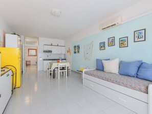 Um apartamento moderno com cozinha compacta, sala de jantar e sala de estar com sofá e obras de arte na parede.