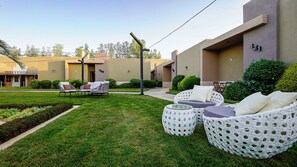 A modern outdoor seating area with wicker furniture and a well-maintained lawn.