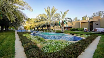 A landscaped pool area with a tiled border, surrounded by well-maintained grass and shrubs.