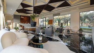Een moderne lobby met een zithoek, een receptiebalie en grote ramen met uitzicht op het landschap.