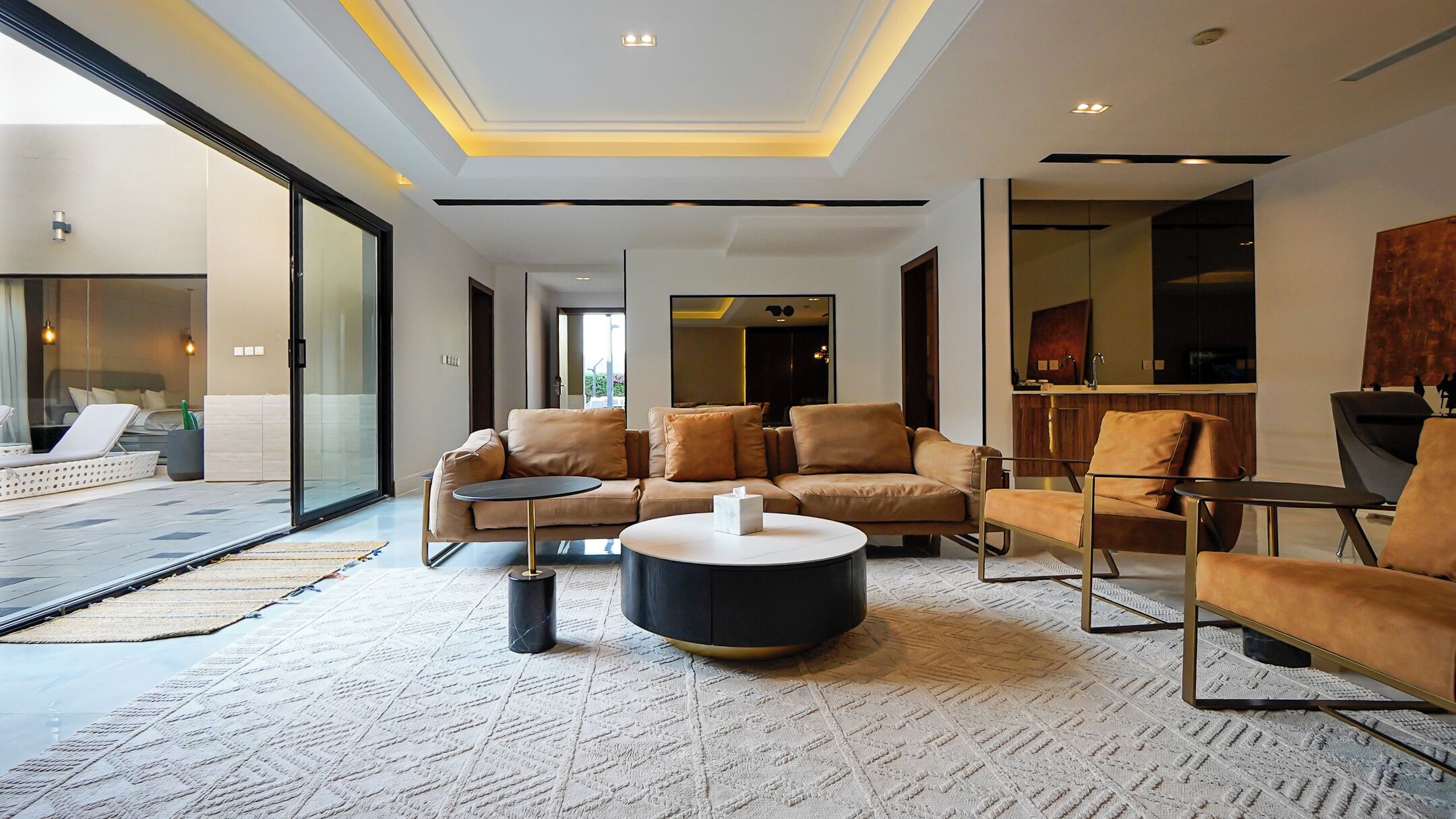 A modern living room with a sectional sofa, a round coffee table, and a dining area with a bar.