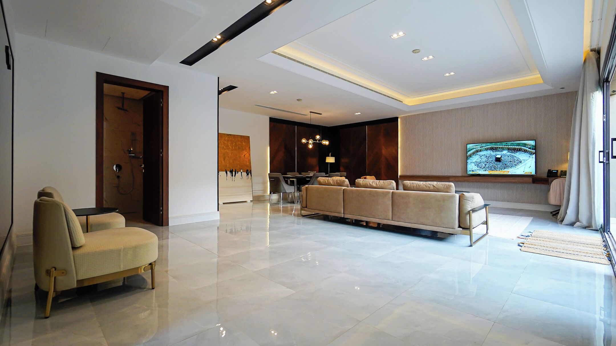 A modern living room with a sofa, a television, and a dining area.