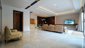 A modern living room with a sofa, a television, and a dining area.