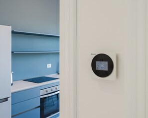 A kitchen with a modern stove, oven, and a wall-mounted thermostat displaying 25 degrees Celsius. - Casa della Pace Apartment (Orvieto)