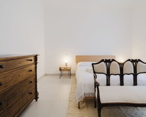A bedroom with a wooden dresser, a bedside table with a lamp, a bed with a headboard, and a rug. - Casa della Pace Apartment (Orvieto)