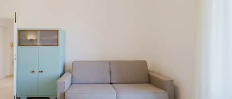 A room with a light blue cabinet, a grey sofa, and a white rug.