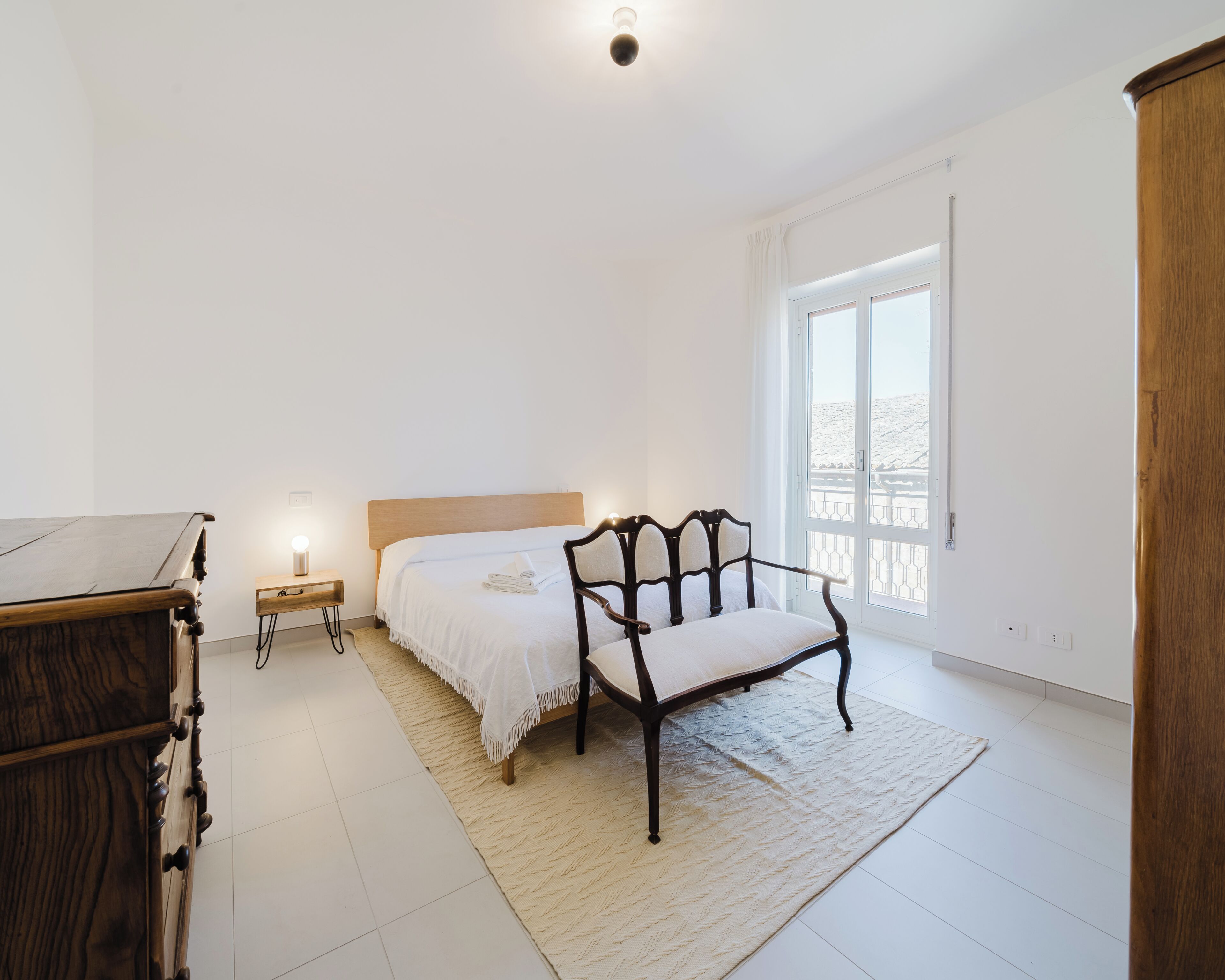 Ein Schlafzimmer mit einem Bett, einem Holzstuhl, einem Nachttisch und einem Kleiderschrank.
