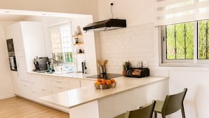 A modern kitchen with a large island, bar stools, a microwave, and a window with a view of greenery. - Villa de Flore, sea view with private pool, 15 minutes from the beaches🌴and renovated (La Possession)