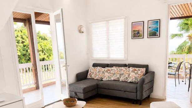 A living room with a grey sectional sofa, a round wooden table, a grey ottoman, and a glass vase. - Villa de Flore, sea view with private pool, 15 minutes from the beaches🌴and renovated (La Possession)