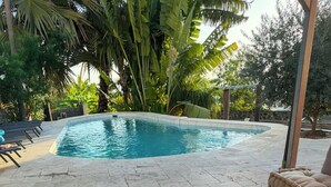 A poolside area with a wooden table, colorful glasses, and a sofa. - Villa de Flore, sea view with private pool, 15 minutes from the beaches🌴and renovated (La Possession)