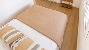 A bedroom with a bed, a small round table, a hanging light fixture, a door, and a wall-mounted shelf. - Villa de Flore, sea view with private pool, 15 minutes from the beaches🌴and renovated (La Possession)