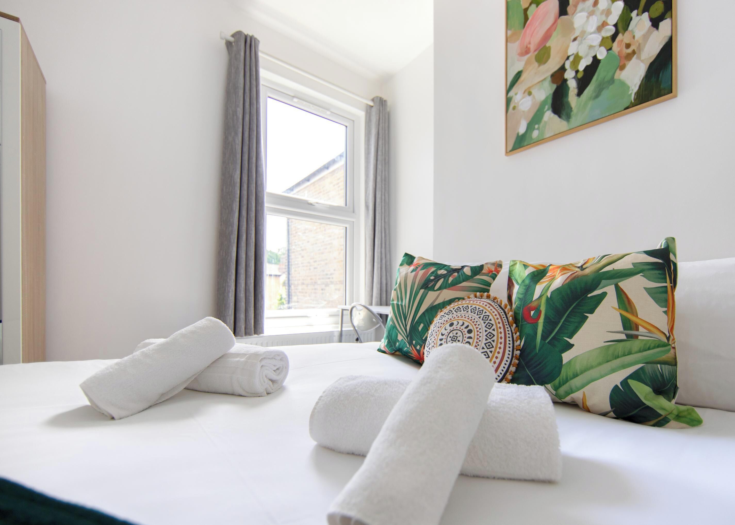 A hotel room with a bed, pillows, and a window.