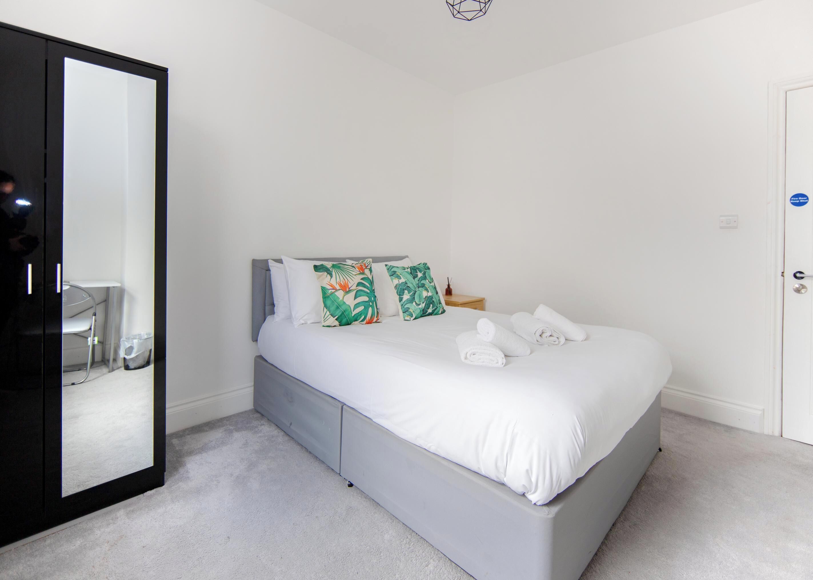 Une chambre à coucher avec un lit, un grand miroir et une porte.