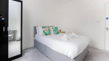 A bedroom with a bed, a large mirror, and a door.