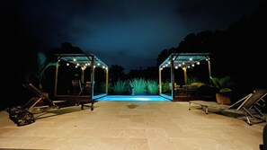 An outdoor pool area with two covered seating areas, each with string lights and chairs. - Villa Les Alpinias: A Serene Oasis with a Private Pool (Petit-Bourg)
