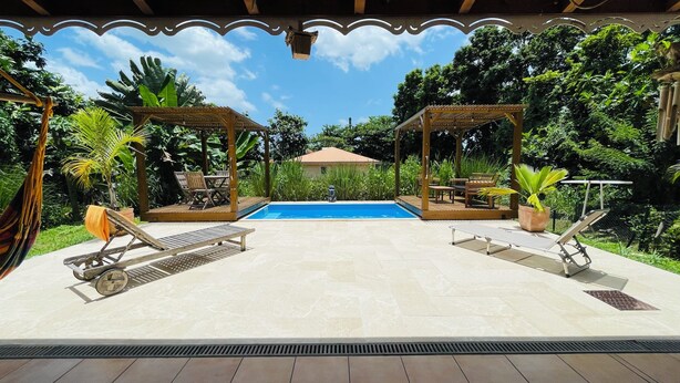Un espace piscine agrémenté de deux pergolas en bois, de chaises longues et d’une piscine à l’eau d’un bleu cristallin.