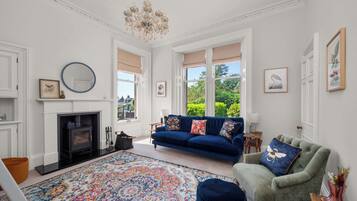 A living room with a fireplace, a blue sofa, a green armchair, and a colorful rug.