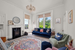 A living room with a fireplace, a blue sofa, a green armchair, and a colorful rug.