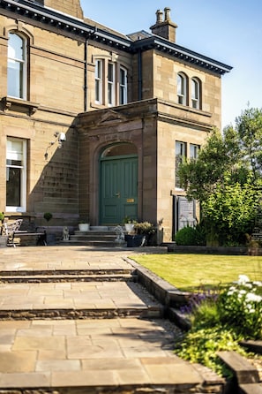 A historic building with a green door, stone steps, and a garden.