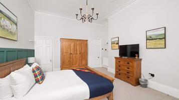 A bedroom with a bed, wooden wardrobe, television, and artwork on the walls.