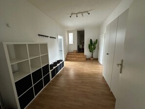 Ein Korridor mit Holzboden, weißen Wänden und einer Treppe, die in einen anderen Raum führt.