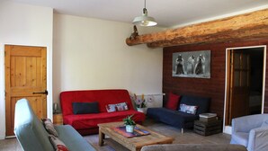 A living room with a red sofa, a blue sofa, a wooden coffee table, and a grey armchair.