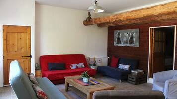 Een woonkamer met een rode bank, een blauwe bank, een houten salontafel en een grijze fauteuil.
