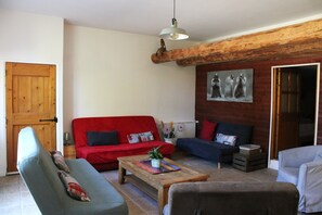 A living room with a red sofa, a blue sofa, a wooden coffee table, and a grey armchair.