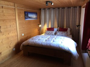 A wooden-paneled room with a bed, a nightstand, a lamp, and a painting on the wall.